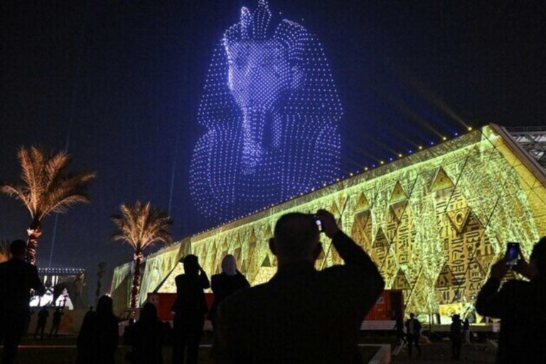 Lightning effects depicting the funerary mask of ancient Egyptian King Tutankhamun light up the sky during the opening ceremony of the Grand Egyptian Museum (GEM) in Giza, on the southwestern outskirts of the capital Cairo on November 1, 2025. Near the ancient Pyramids of Giza just outside Cairo, the Grand Egyptian Museum is gearing up for a lavish opening on November 1, after two decades of delays. Massive statues and historic artefacts from the country's ancient civilisation will be on display across the 24,000 square metres (258,000 square feet) of permanent exhibition space. (Photo by Khaled DESOUKI / AFP)
